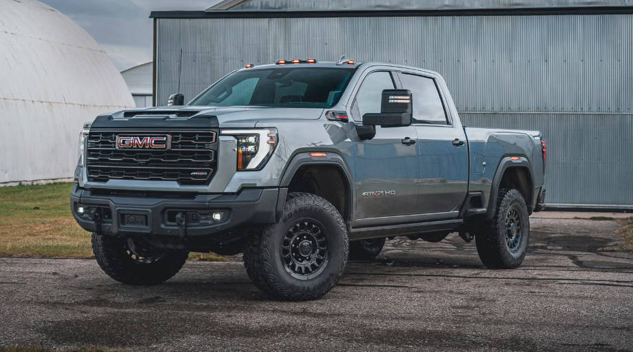 Gray GMC Sierra HD AT4X truck parked on pavement in front of a metal building.